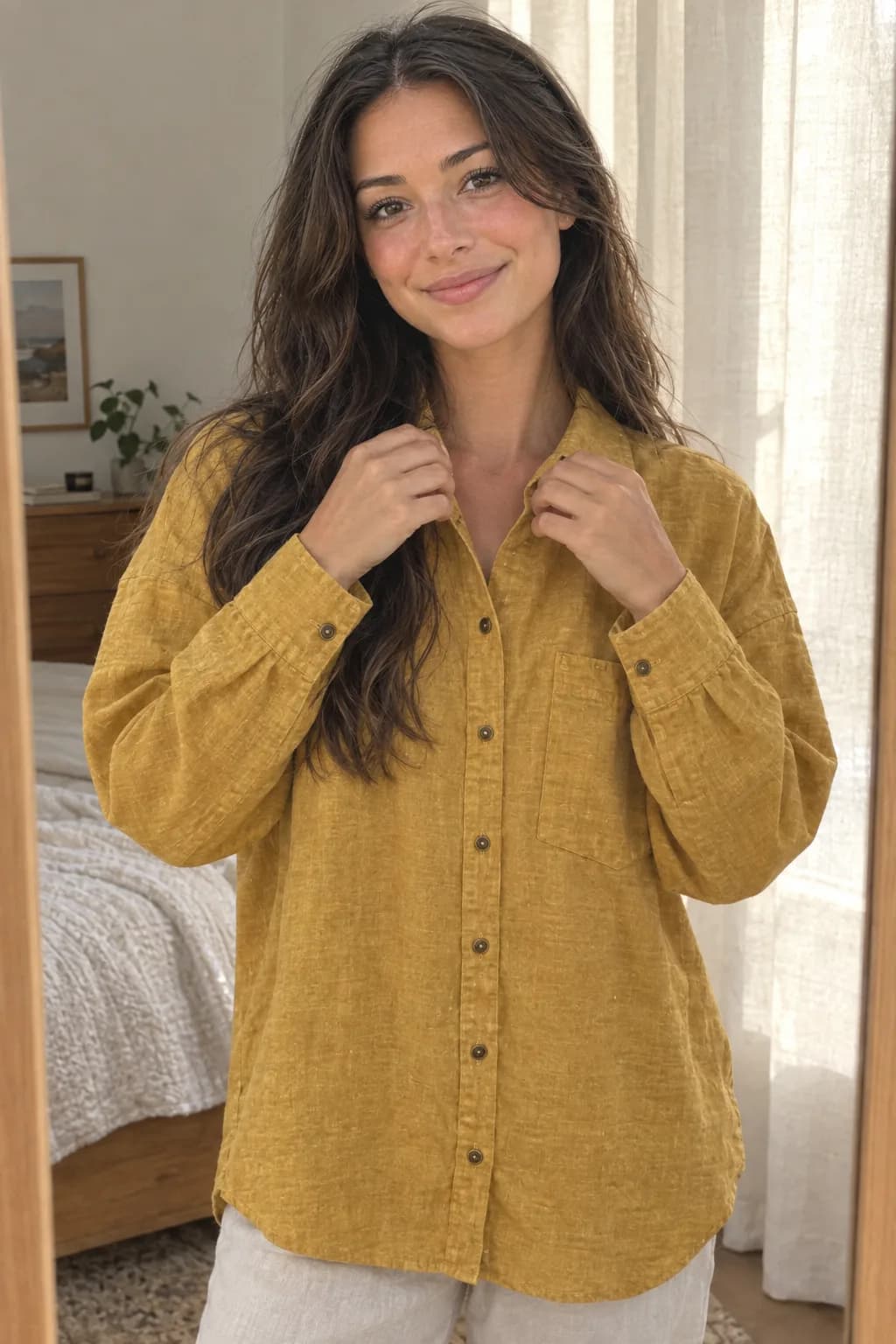 Model merapikan kerah kemeja linen mustard di depan cermin