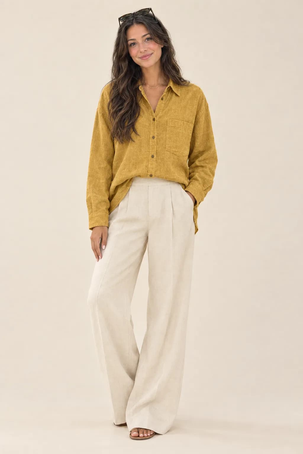 Model mengenakan kemeja linen mustard dengan celana krem